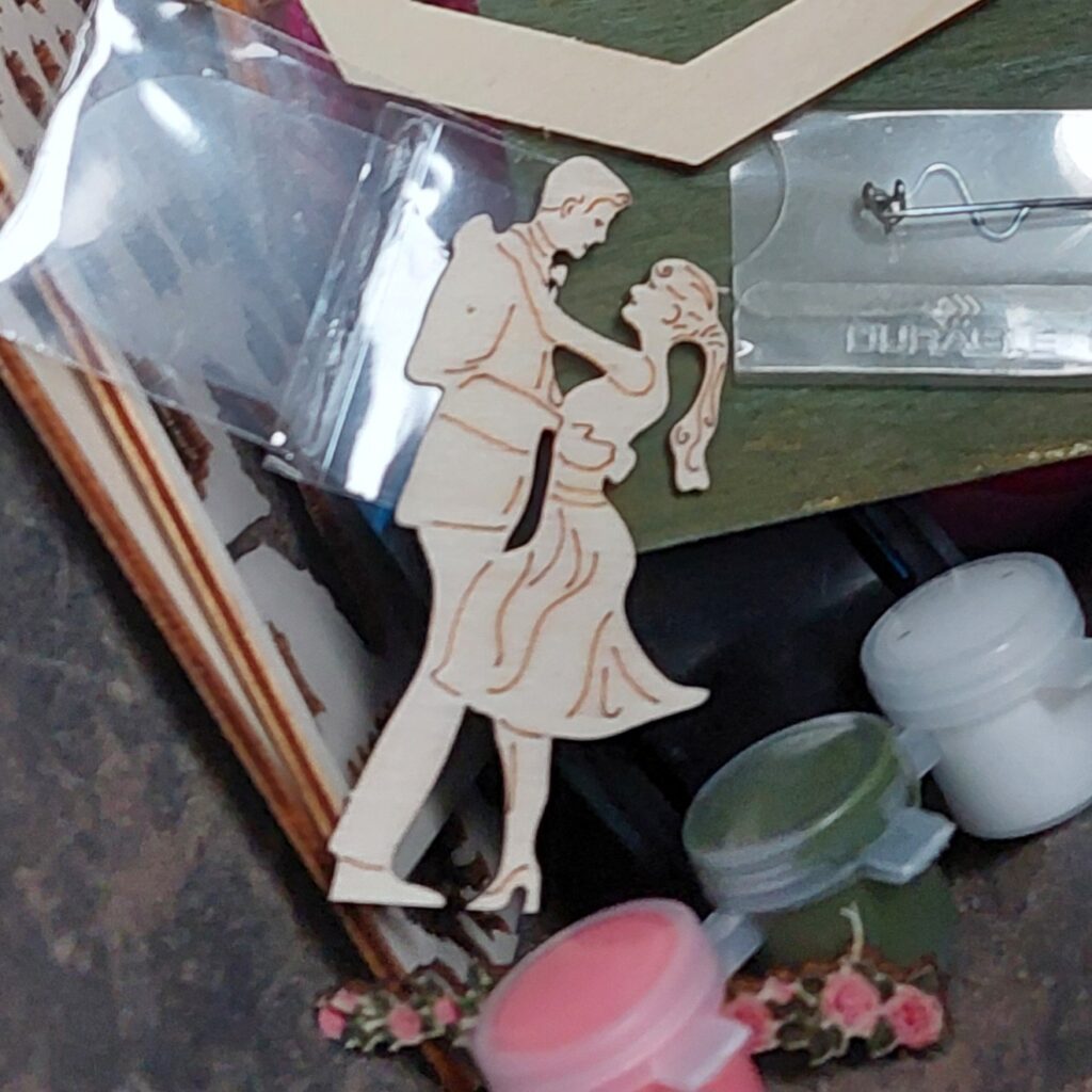 Ein unvollendetes 3D-Steckpuzzle mit der Holzfigur eines tanzenden Paares liegt zwischen Bastelmaterial. Ein Symbol für Dinge, die gehen dürfen und dennoch inspirieren.