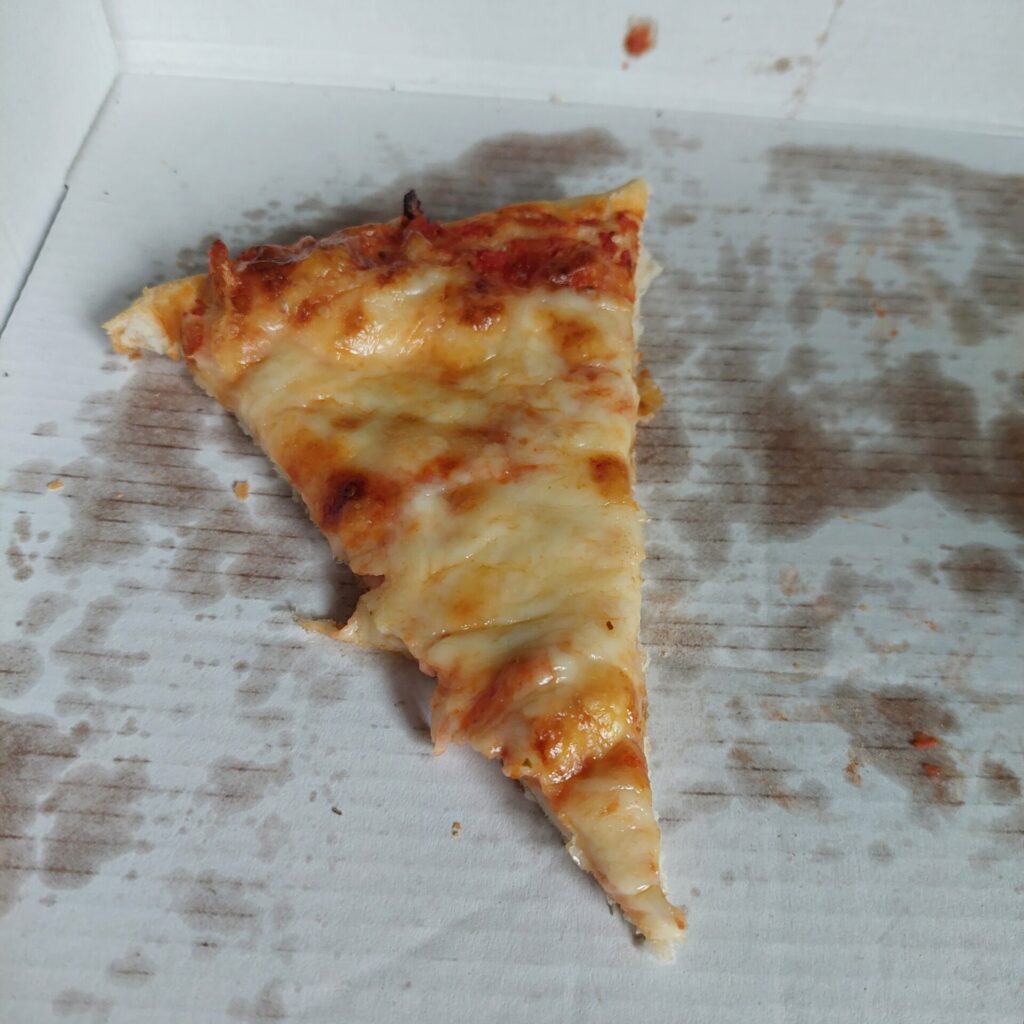 Ein Stück Pizza liegt auf fettigem Papier