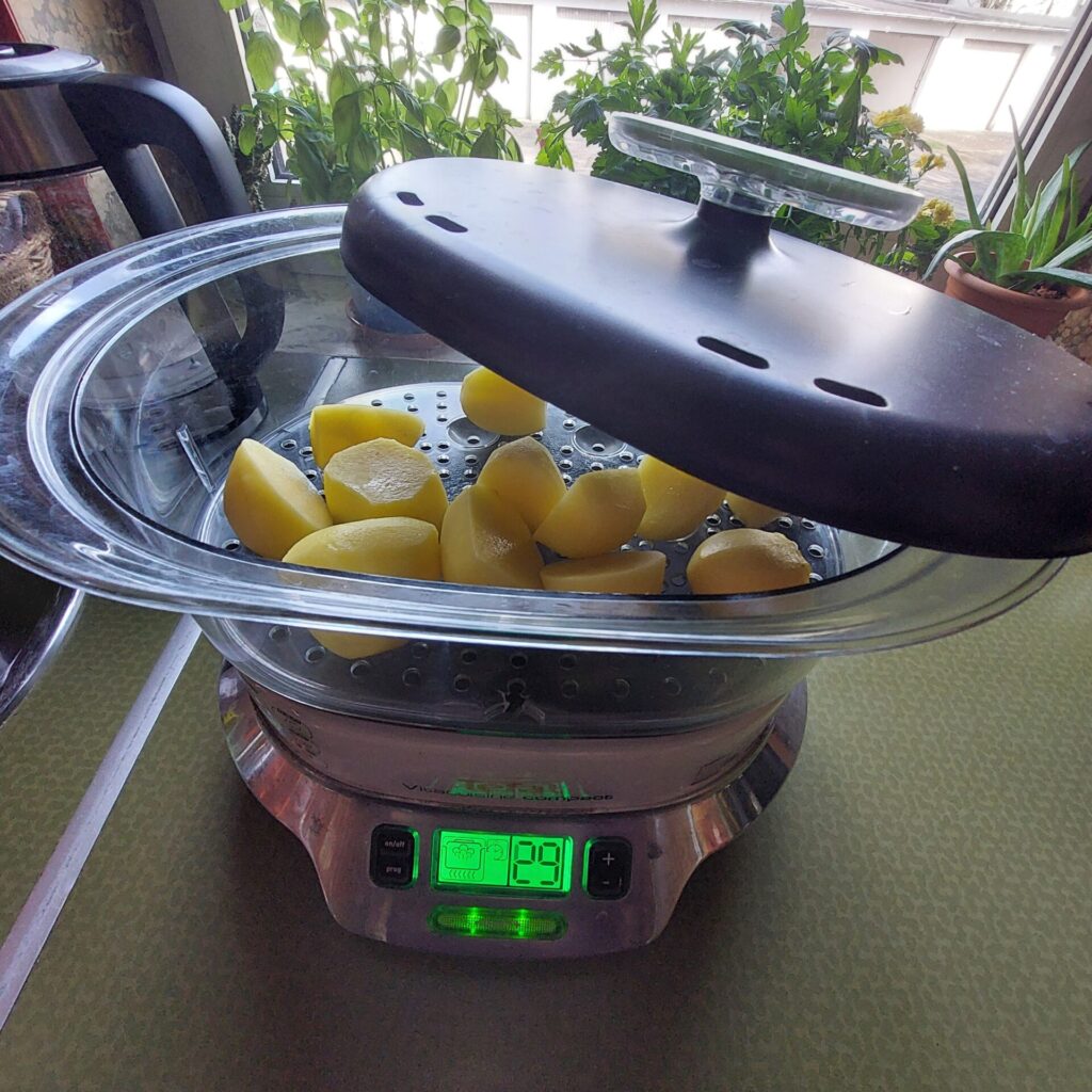 eschälte Kartoffeln liegen im Einsatz eines elektrischen Dampfgarers auf der Küchenarbeitsfläche.