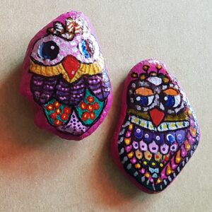 Zwei farbenfrohe Steineulen in Pink- und Lilatönen, detailreich bemalt