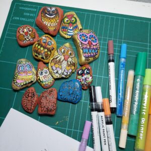 Sammlung bemalter Steineulen in verschiedenen Stadien – von Skizze bis fertig