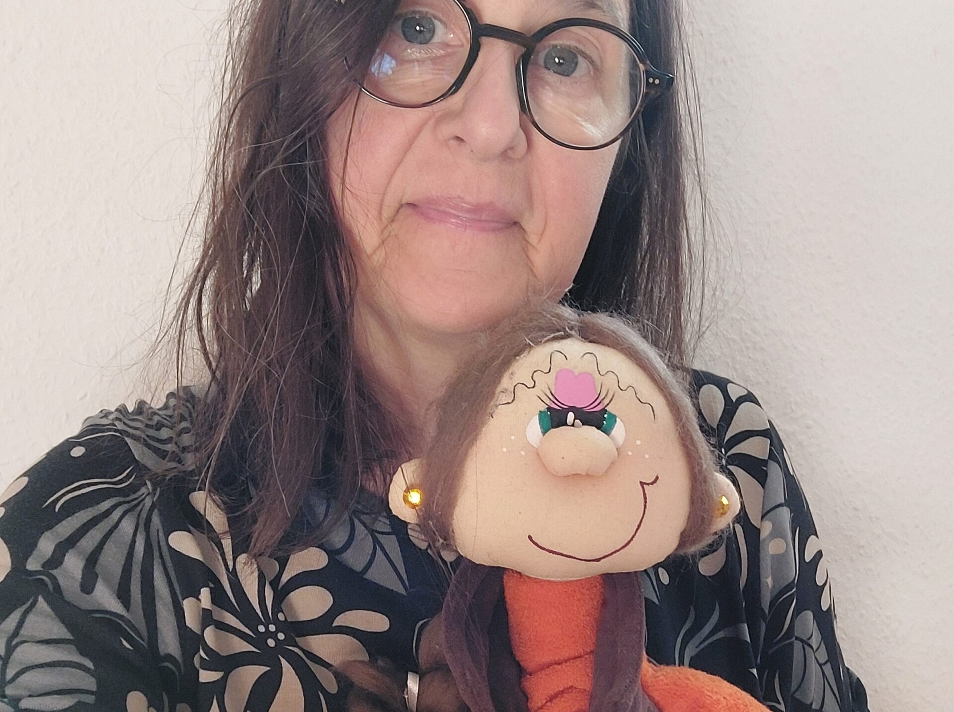 Frau hält eine Puppe als Symbol für das innere Kind nah bei sich – Behausung als innere Beziehung.