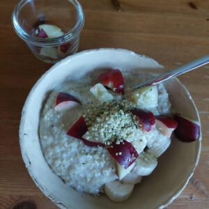 Haferbrei mit Banane, Nektarine und Hanfsamen in einer Schale.