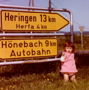 Kleines Mädchen steht neben großen Wegweisern.